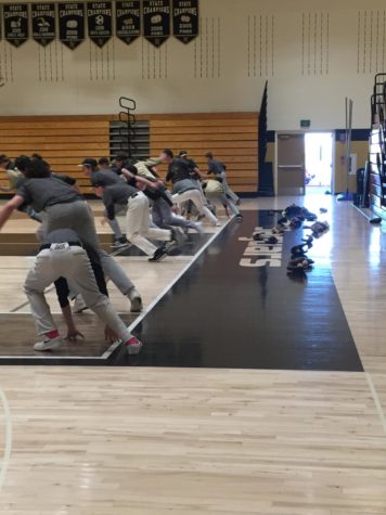 The boys baseball players reach down to touch the baseline for another sprint in the main gym during practice, Monday, Mar. 5.  The boys baseball practice had been moved inside due to strong winds and cold temperatures outdoors.
