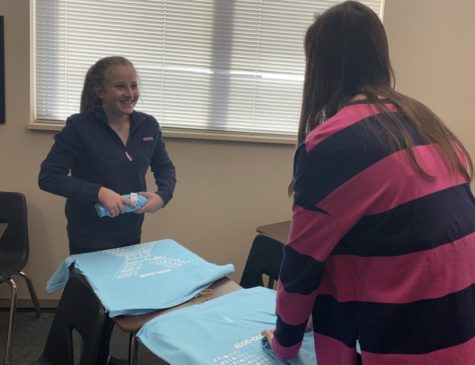Sophomores Emma Renard and Hailey Poppler fold shirts to be packaged for Wish Kit sales. Student Council ordered about 2,600 shirts so the whole student body has a chance to buy a shirt. It supports the Wish Kid... Everyone gets one, its kind of a big thing, council member Berlin Barnett 21 said.