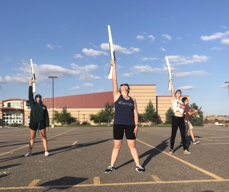 Anitra Dolan ‘20, Morgan Williams  ‘20, and color guard instructor Marguerite Buhr practice a new routine after practice in the upper parking lot Aug. 27. This was the first night the color guard section learned rifle work for movement three. 