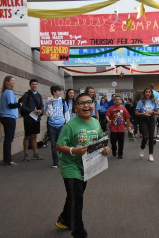 Fabian laughs while holding a copy of the Rock in the main hallway Feb. 21. Student Council took Fabian and his family on a tour of the school after the Opening Assembly to show off the decorations.