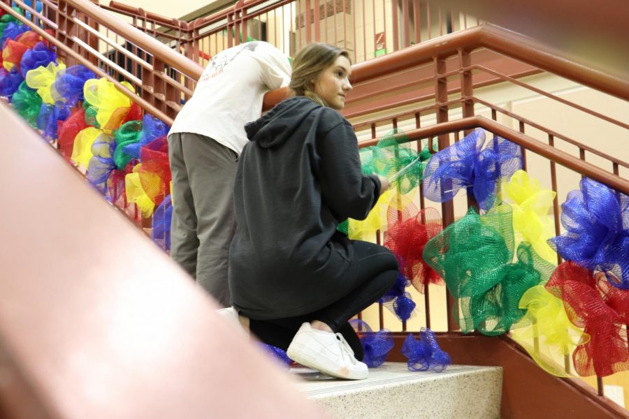 Madeline Ramsey 22 ties colorful puffs to the railing of the main staircase. 
