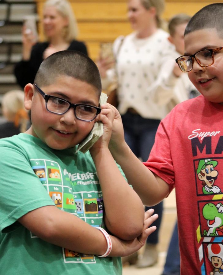 Fabian and his brother, Martin play with a stack of dollar bills collected during the Miracle Minute Feb. 21. Fabian’s brother engaged with him throughout the opening assembly, both expressed their excitement as family watched on.