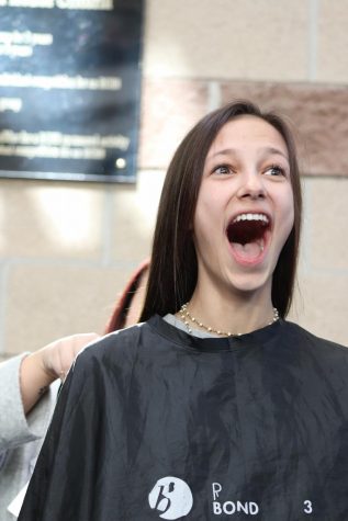 Outside the performing arts wing, Kelsey Buffington ‘22 gasps while she donates her hair for the Dare To Share Your Hair event  Feb. 27. Behind the barricades, Buffington’s friends watched on and shouted supportive compliments to her.
