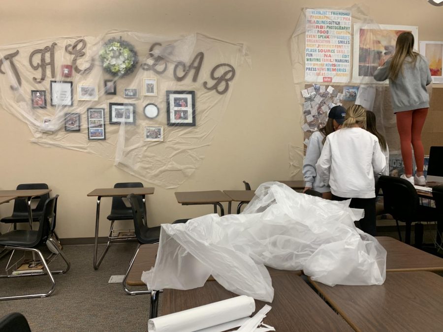 Yearbook students cover wall decorations in room 4113, to prepare for the cleaning over spring break March 13. After announcing a two-week school closure, the district also announced that schools would be sprayed down over spring break with industrial chemicals, to counter the coronavirus. 