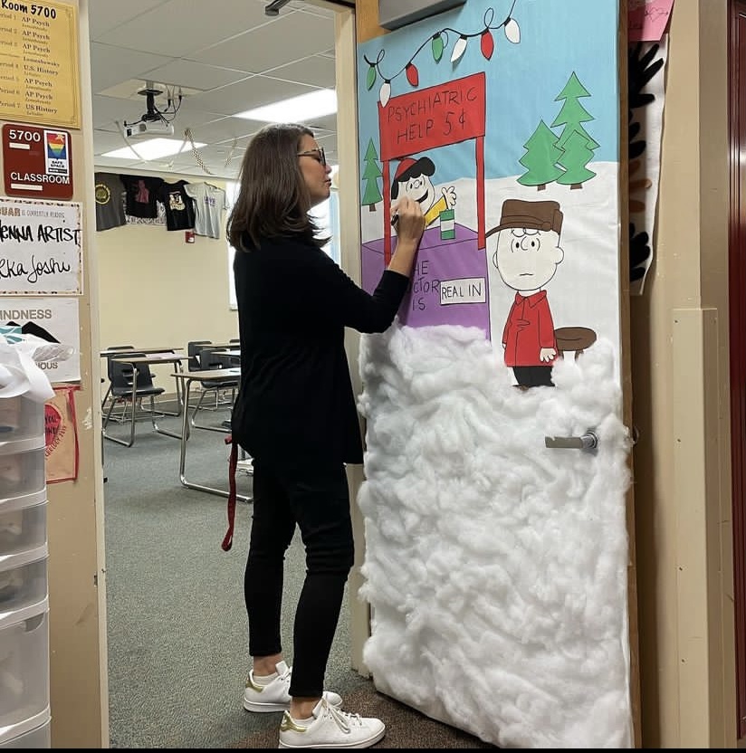 AP Psychology teacher Kathryn Lemeshewsky decorates her classroom door for a door decorating contest in the 5000s pod Dec. 8. Lemeshewsky organized the contest as an opportunity for teachers to take part in something fun and creative before break. Teachers had to do 51% of the work themselves, with their doors theme connecting to the holidays or the subjects they teach. Quite honestly, the social studies pod has gotten a little lame, and Im done with that. Im ready to boost the spirit in the 5000s pod and Im trying to do things to get us all to contribute more, because I like the people in our department, Lemeshewsky said.