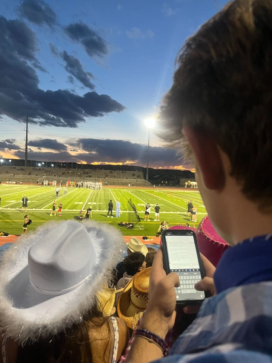Kyle Walsh ‘25 multitasks between homework and watching the game at the varsity football game against Smoky Hill High School at Echo Park Stadium Aug. 31. Walsh worked on notes for AP Environmental Science (APES). “In general, I have lots of homework in all of my classes, so I put off my APES notes because they are easier to do when I have spare time,” Walsh said. “Tonight, I didn’t have spare time to do my notes since I was going to the game, so I did them here.” 