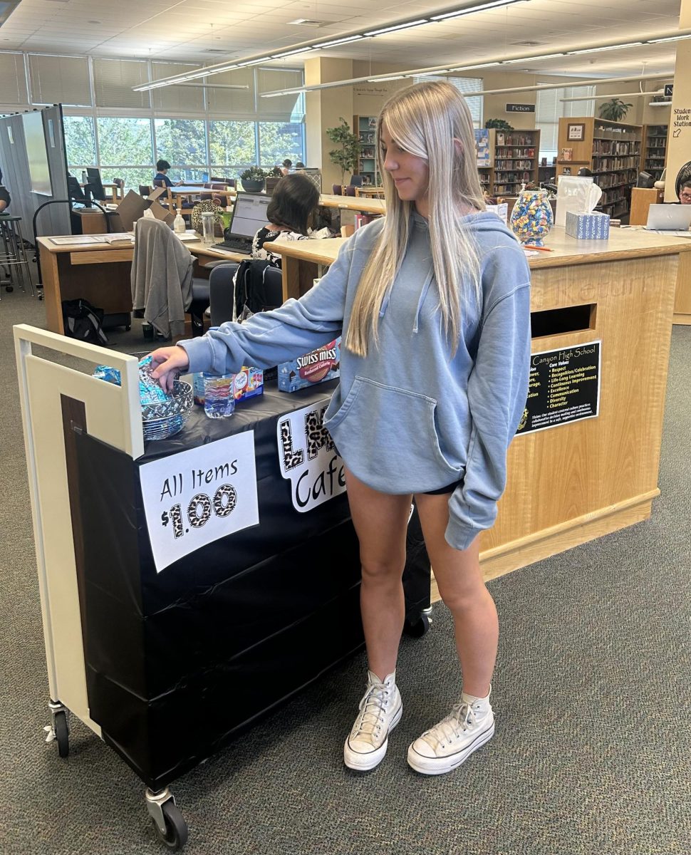 Avery Pfannenstiel ‘26 purchases a Rice Krispies Treat from the food cart in the LMC Sept. 5. The cart also offered a variety of other snacks to choose from, such as hot cocoa, all at the cost of $1. “I think the cart is a good idea for Rock Canyon. It raises money [for the school],” Pfannenstiel said.