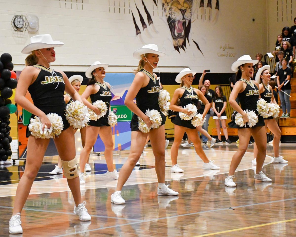 Gianna Peterson ‘25 and other fellow Poms dancers perform a dance inspired by the Western Spirit Day during the Homecoming Assembly in the gym Sept. 21. Homecoming week consisted of five spirit days, including Freedom Friday, Tropical Florida Monday, Bama Rush Tuesday, Wild West Wednesday and Home Colorado Thursday. “It was awesome to perform and we had a lot of practice [in preparation],” Peterson said.  