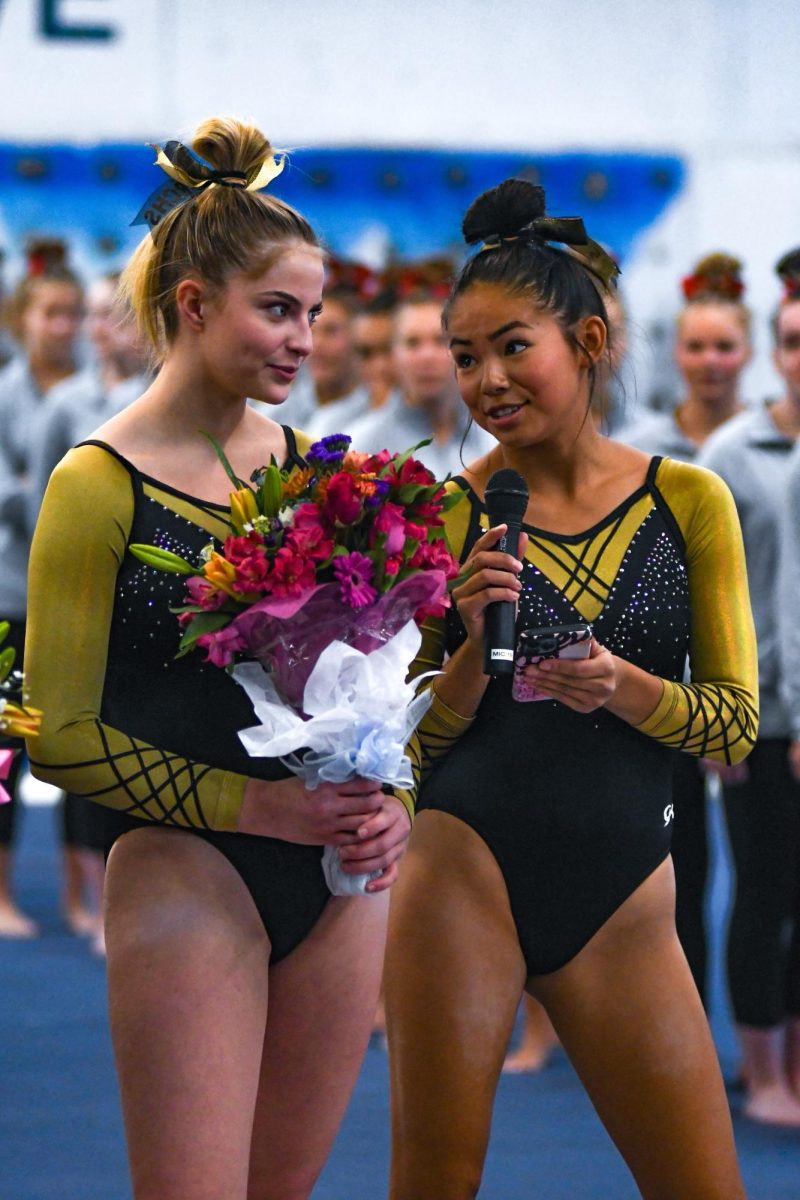 Varsity gymnasts Jordan Engerman ’24 and Ava Martinez ’25 stand in front of the mat during Senior Night before the meet against Heritage High School’s combined team Oct. 7. During Senior Night, the team recognized six seniors on the team with flowers and speeches. The team is composed of students from Thunder Ridge, Mountain Vista, Highlands Ranch, Valor Christian and Douglas County High School students, and sponsored by Rock Canyon. “I have been on the team for four years,” Engerman said. “My favorite part of being on the team has been meeting some of my best friends.”