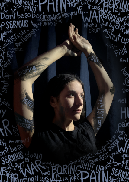 Sophia Miller 25 poses for a creative photo. The text and darkness convey the negative emotions and thoughts given to us by others. In a world full of negativity, these ideas ingrain themselves into our lives and contribute to the isolation so prevalent in everyday life.