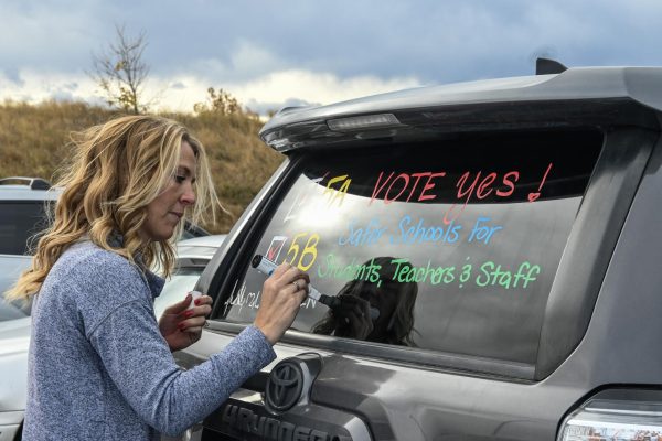Assistant Principal Mandi Zimmerman uses car markers to write messages in support of passing 5A and 5B on cars in the upper lot during Parent Teacher Conferences Oct. 12. As Assistant Principals, Zimmerman and Karli Bloom did not need to meet with parents, painting an estimated 40 cars. Teachers and parents marked their cars with sticky notes if they wanted their cars painted. On the evening of conferences, Ms. Bloom and I were not officially working that evening, we had prearranged absences.  We were using our personal time to write on the cars with Mr. Abners permission, Zimmerman said.