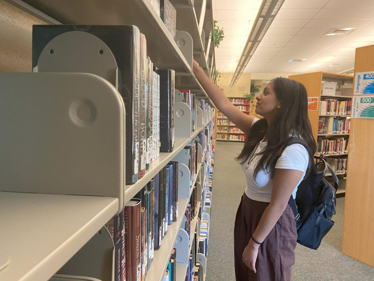 Reva Mehrotra ‘26 looks at books in the library Oct. 10. After classes students finished their classes, they hung out in the library, completing homework while also socializing with their fellow peers. Mehtrotra went around the bookshelves and looked at different novels. “The library is great because studying with my friends keeps me productive,” Mehrotra said. 