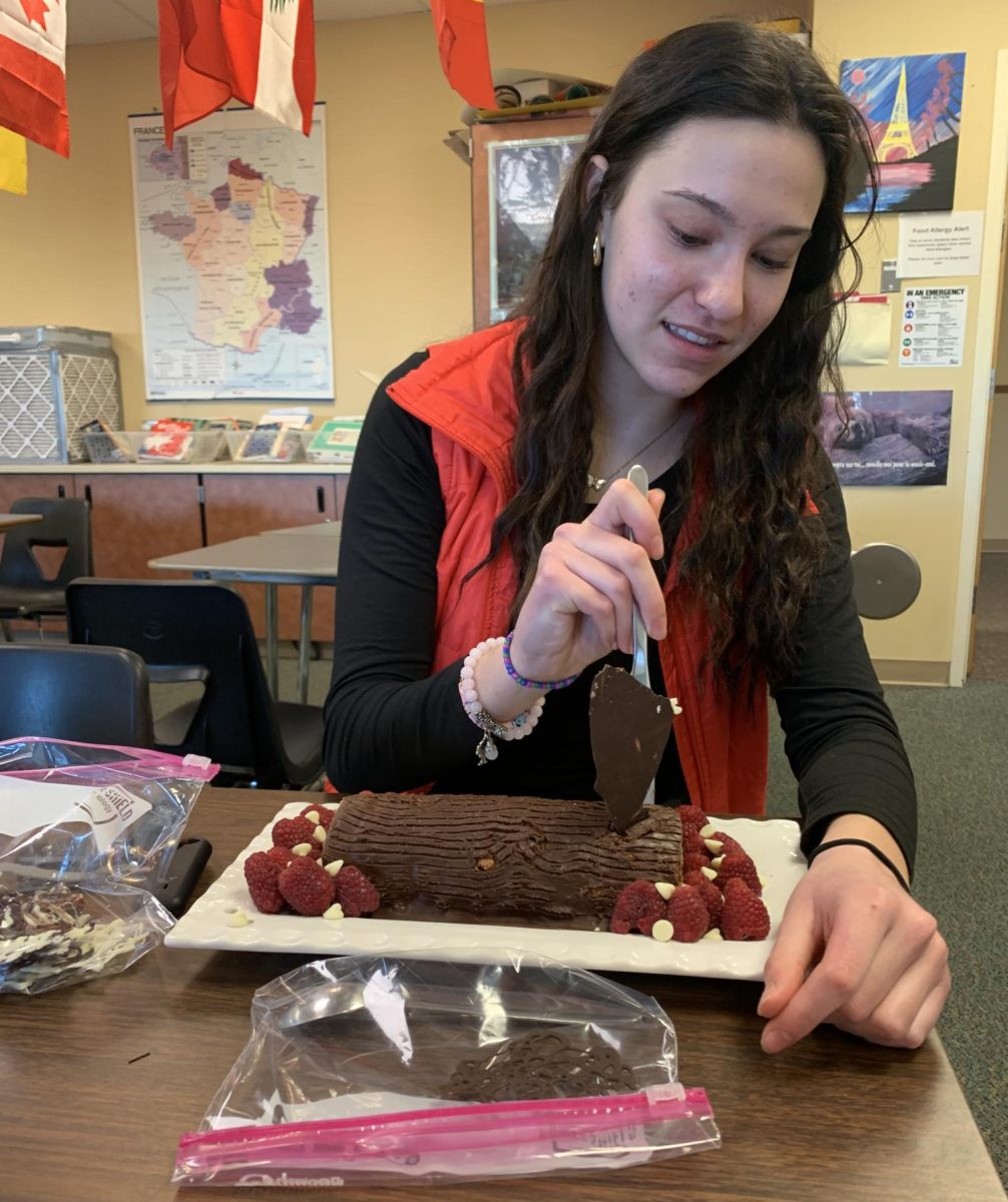Amelia Solano ‘25 cuts her homemade Bûche de Noël, also known as Yule Log cake, during Alexis Savas’s second period French 5 Dec. 11. Five of 10 students in the class brought in cakes as part of an optional extra credit competition. Solano’s cake, composed of chocolate sheet cake, chocolate ganache, raspberries, white chocolate chips and chocolate shards, won first place in the “Appearance” category. Votes were cast by teacher judges and classmates. “I spent about half a day on my [cake] because I’m a perfectionist. I was very proud of my decorations and I had worked really hard, so winning was very rewarding and I appreciated everyone’s compliments on my bûche,” Solano said. “I loved the whole competition and I really appreciate how Mrs. Savas allows us to do this to connect to French culture.” Reporting by Claire Bauer