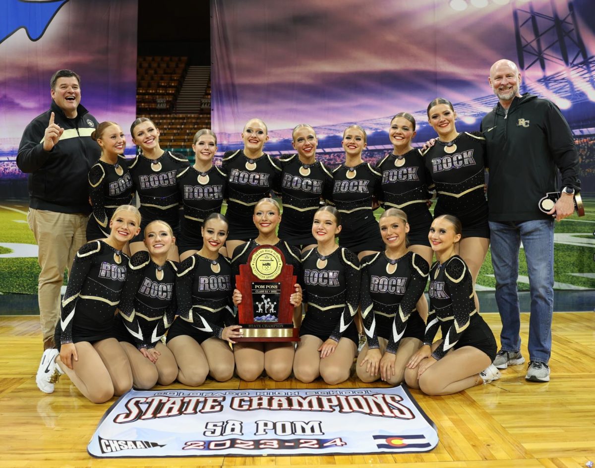 Principal Andrew Abner, the varsity poms team and Athletics Director Tom Brieske smile with the State trophy and poster after being announced as State Champions Dec. 9. This was the team’s sixth state championship win in school history. “When they announced us [as] the winners, we were all so excited and relieved that our work had paid off. Our next step is Nationals,” varsity poms dancer Harper Rank ‘25 said.