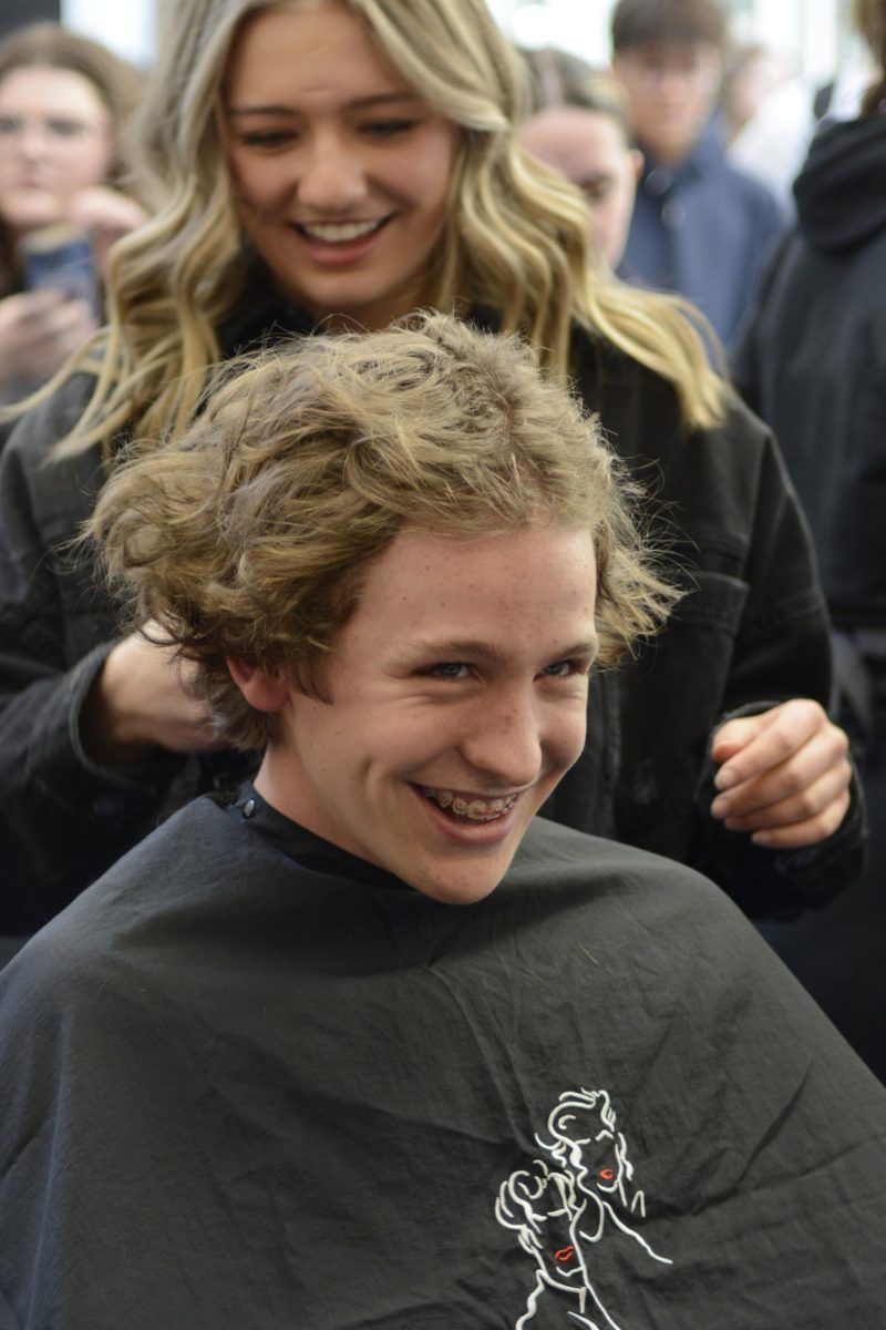 During the Dare to Share Your Hair event March 5, Carter Buckman ‘27 smiles as he gets a buzz cut near the main entrance of the school. High school cosmetology students from Douglas County performed all haircuts, allowing them to practice and gain experience. Participants, including students, teachers, and administrators, were charged $5 per haircut, with all proceeds benefiting Kiki’s Wish and providing wigs for cancer patients. “I did it to donate hair to someone who needs it more. I think it’s really important for others to share their hair and support the cause,” Buckman said.