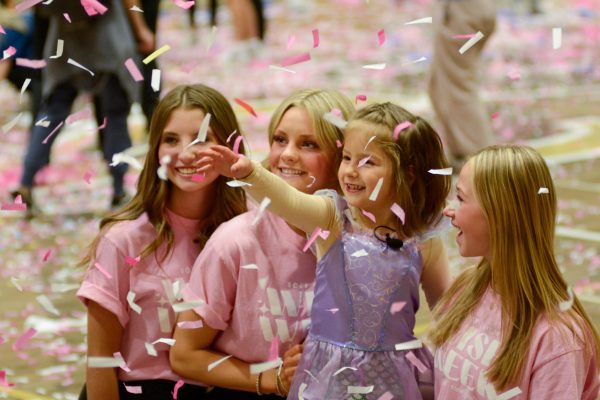 2024 Wish Kid, Kiki, reaches for confetti while taking a picture with Student Council (StuCo) members Jade Spears 24, Ella Oates 25 and Hailey Anderson 26 after the Wish Week closing assembly in the gym March 8. During the assembly, Kiki and Choir sang
Part of Your World from the
Disney Movie The Little Mermaid before pieing math teacher Austin Bennett in the face. Kikis younger brother, Demitri, shaved his head in her honor while she sang in front of the student body. As StuCo stood with their posters, it was announced that the school raised $94,921.91, over $33,929.58 more than was raised the year prior. Its really cool to be a part of Rock Canyons most successful Wish Week as a senior, StuCo member Brady Hill 24 said. We took it to the next level this year; we raised around $94,000 and granted 12 wishes, including Kikis. I thought the closing assembly this year was hilarious when we switched the nine and four around to start, and surprised everyone by showing the true amount.