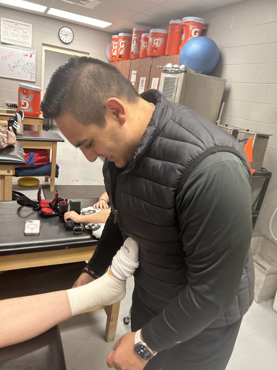 Taylor Quenzer tapes an athlete’s ankle during seventh period in the athletic training room Jan. 23. This is Quenzers third year working at the school.