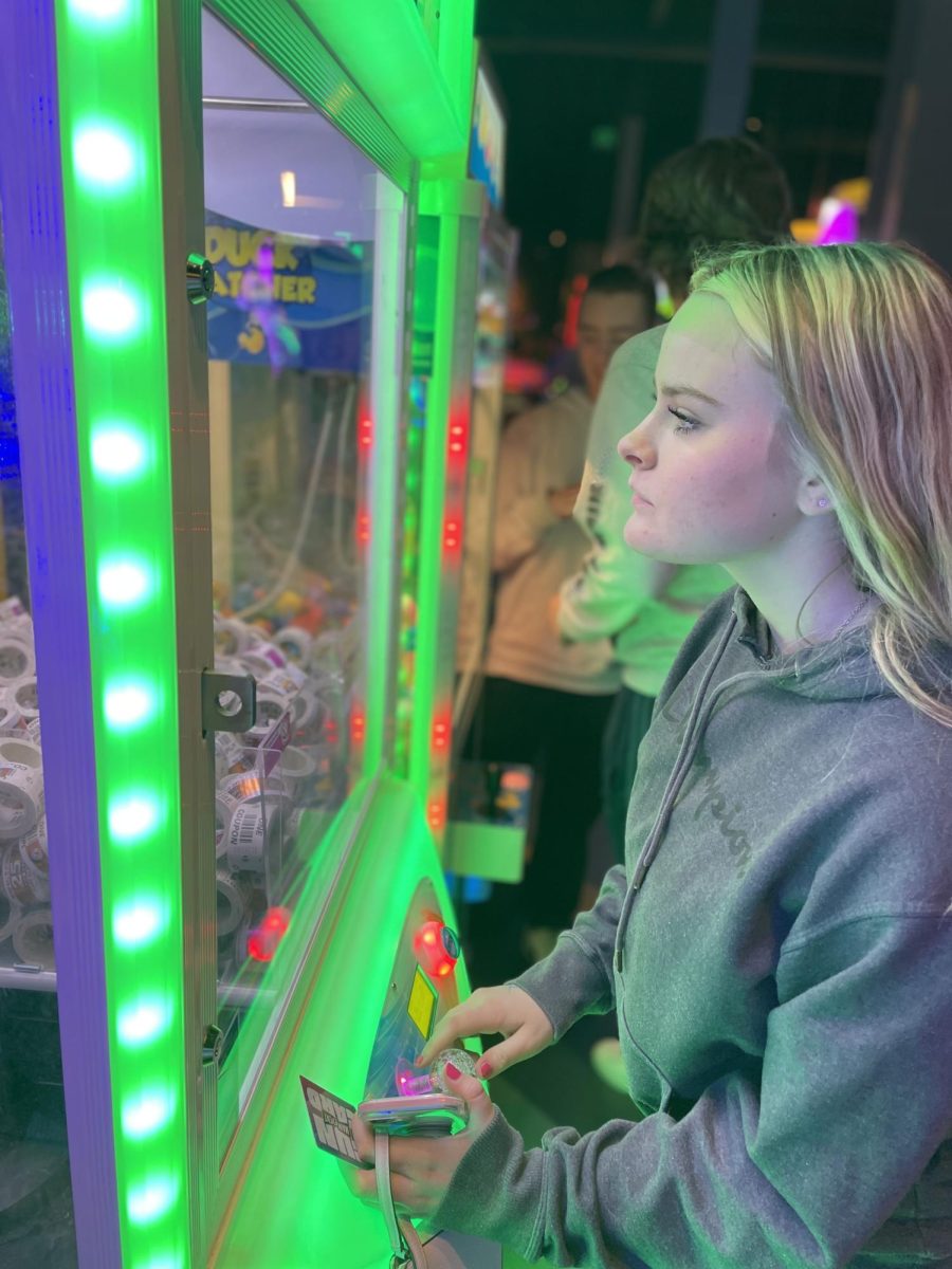 Lauryn Wilkey ‘26 uses the claw machine in an attempt to win tickets to spend on various prizes such as candy, toys, electronics, and more at Main Event March 6. Rock Canyon’s Student Council (StuCo) held Wish Week events such as Main Event to raise money for this year’s Wish Kid, Kiki. StuCo collected 20% of the sales from Main Event to go to the Make-A-Wish Foundation. “I’m here to support our school and Kiki while also trying to have some fun and win prizes, as most people are,” Wilkey said.