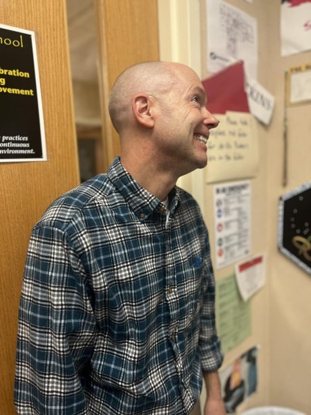 English teacher Andrew Watkins smiles at the entrance walls of his classroom Dec. 4. Watkins classroom is lined with posters, pictures and gifts from students that showcase his teaching experience. I am still excited about what I teach, Watkins said, And hopefully that comes across. Although teaching wasnt my plan, Im glad I did it. It worked out. Im very grateful for the people Ive met.