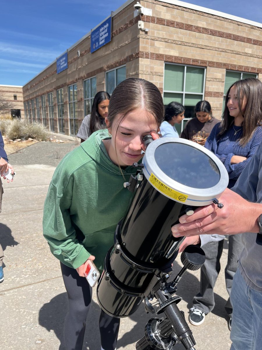 Through science teacher Jack Van Natta’s telescope, Allie Emery ‘27 observes the solar eclipse during third period April 8. The solar eclipse lasted between 11:30 a.m. to 1:30 p.m. with the maximum partial eclipse taking place around 12:40 p.m. About 65.9% of the sun was covered from the school’s angle. Students watched using pinhole viewers, film glasses, the telescope and more. “It’s just something that you don’t see often and when you get to see it it’s really cool. If you miss it, you got to wait, it takes a while. It’s pretty amazing, so if you wanna come out and see it, I think it’s a good thing to take a break from class,” School Resource Officer (SRO) Mark Adams said.