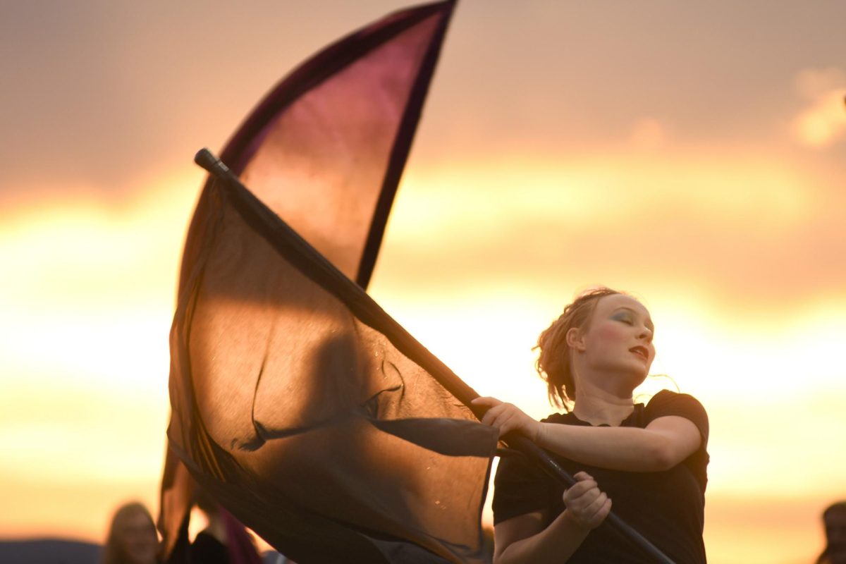 Sophie Harris ‘26 spins the flag during Marching Band showcase performance at Halftime Help Stadium Sept. 11. The Band performed in the Colorado State Showcase alongside other Douglas County schools to receive feedback in order to improve for future competitions. “We have different equipment… I’m part of flag and saber right now,” Harris said.