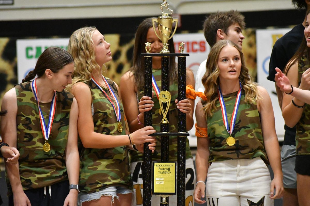 Faith Miller '27 holds her team's trophy as the Powder Puff tournament winner Sept. 19 in the gym during the Homecoming Assembly. Powder Puff was played on Sept. 16 from 6 p.m. to 8 p.m. which resulted in a win for The Hunters. "I was the youngest and only sophomore on the team and it was really cool to help and teach them how to play because some of them didn't know and I have experience in flag football,” Miller said. 
