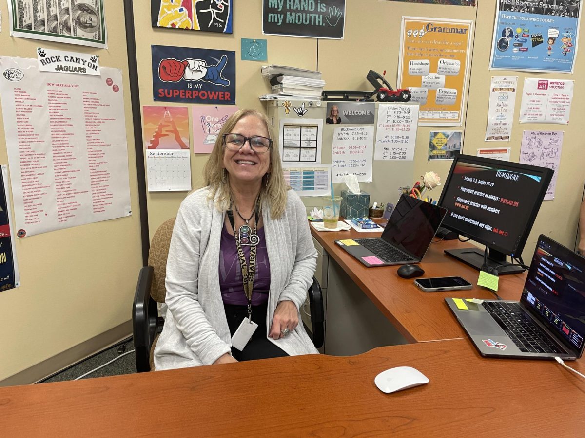 Michelle Greene poses for a photo at her desk in room 8850 Sept. 30. Greene, a Deaf teacher, uses a whiteboard to communicate to her students. “When I first started teaching, oh my goodness, I just realized at that time how beautiful this language is,”  Greene said. “It really woke me up to my own language.” 